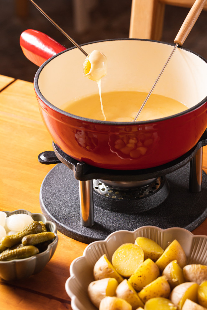 The softened cheese is then scraped onto a plate.Of skinned potatoes, focaccia, cucumbers and onions are served with of raclette cheese